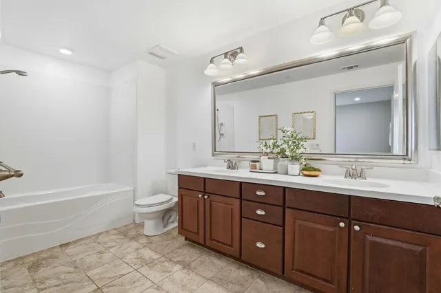 a bathroom with a double vanity sink toilet mirror and bathtub