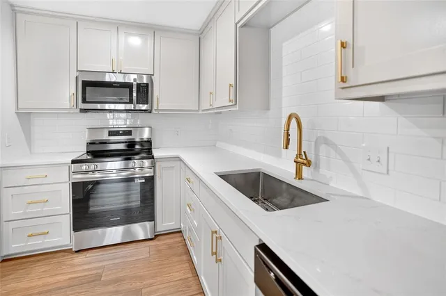 a kitchen with granite countertop white cabinets and stainless steel appliances