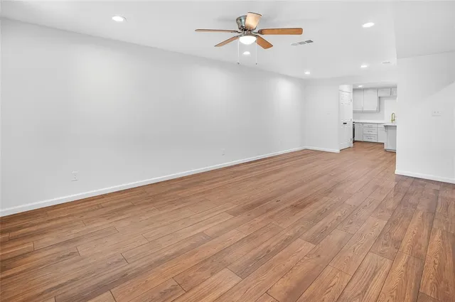 a view of empty room with wooden floor and fan