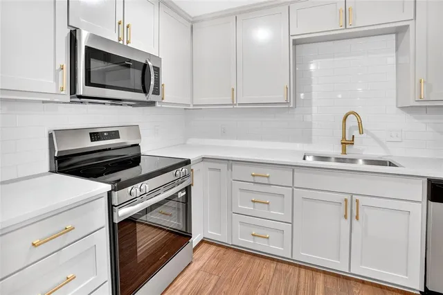 a kitchen with white cabinets stainless steel appliances and sink
