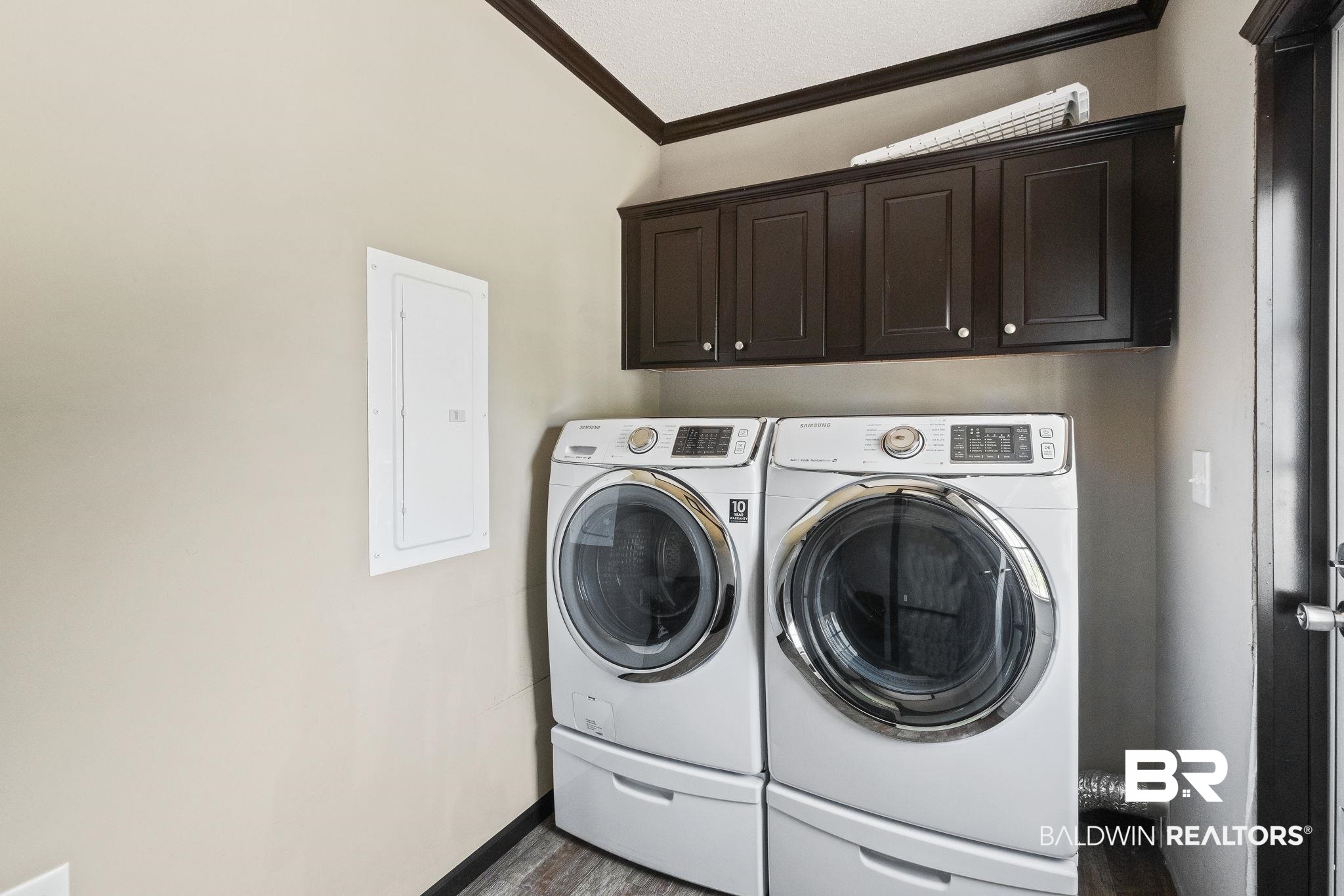 6870 Cecilia Court Theodore, AL 36582 - Photo 28 of 83 Laundry room with electric panel, cabinets, washing machine and clothes dryer, dark hardwood / wood-style flooring, and ornamental molding