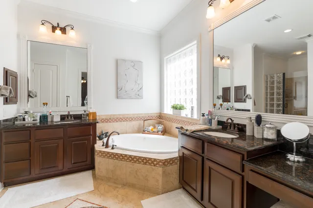 a bathroom with a granite countertop double vanity sink a mirror and a bathtub
