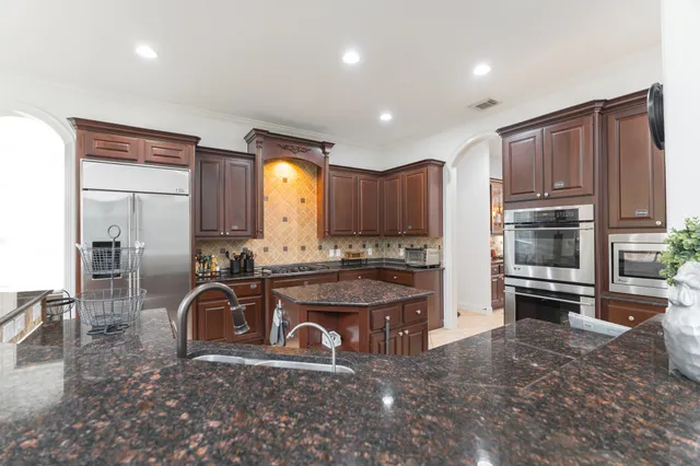 a kitchen with kitchen island granite countertop a stove top oven a sink and cabinets