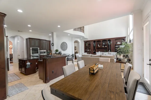 a living room with stainless steel appliances furniture a rug and a kitchen view