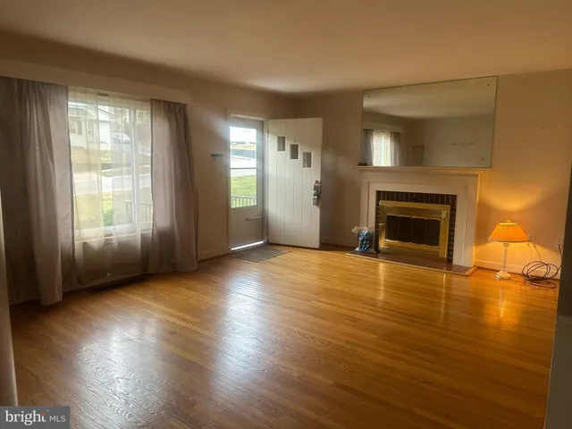 an empty room with wooden floor fireplace and windows