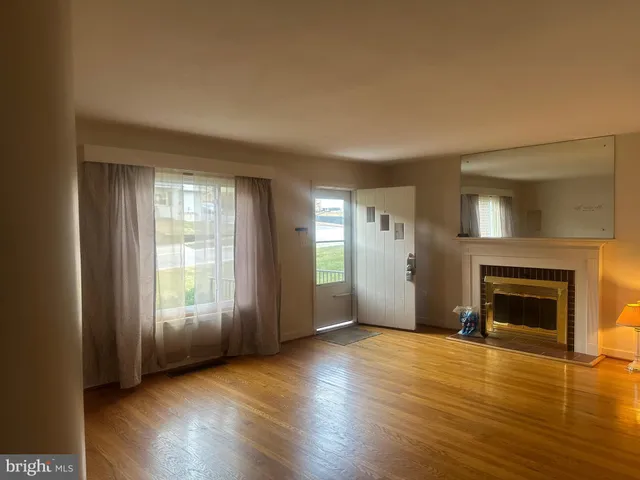 an empty room with wooden floor fireplace and windows