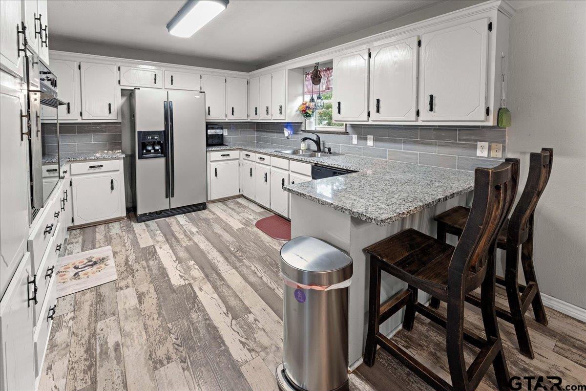 403 Kennedy Street Lindale, TX 75771 - Photo 13 of 36 a kitchen with stainless steel appliances granite countertop a table chairs sink refrigerator and cabinets