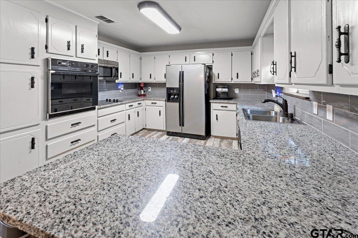 403 Kennedy Street Lindale, TX 75771 - Photo 14 of 36 a kitchen with stainless steel appliances granite countertop a stove a sink and a refrigerator