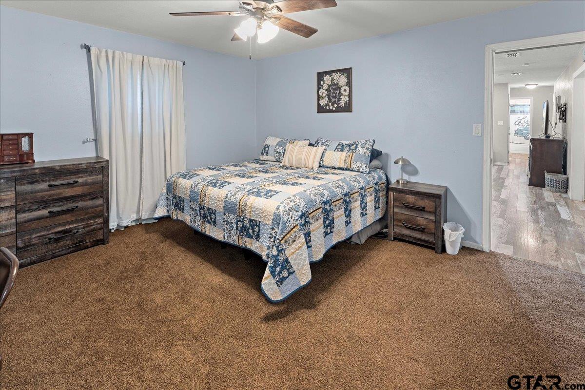 403 Kennedy Street Lindale, TX 75771 - Photo 26 of 36 a spacious bedroom with a bed and a chandelier