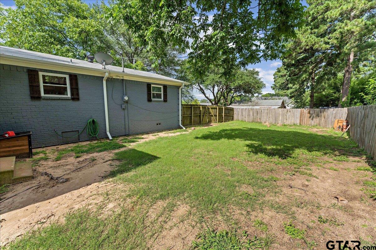 403 Kennedy Street Lindale, TX 75771 - Photo 27 of 36 a backyard of a house with large trees and wooden fence