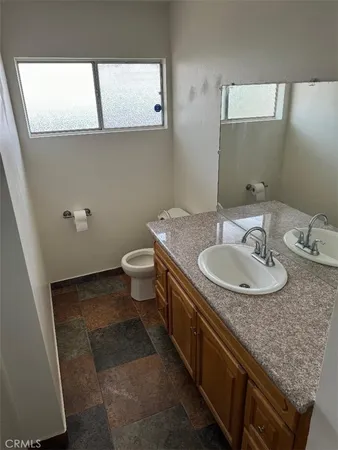 a bathroom with a granite countertop sink a toilet and a mirror