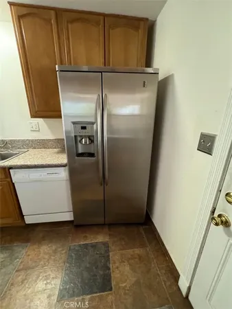 a view of a refrigerator in kitchen and an empty room