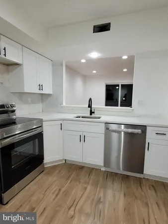 a kitchen with granite countertop a sink cabinets and stainless steel appliances