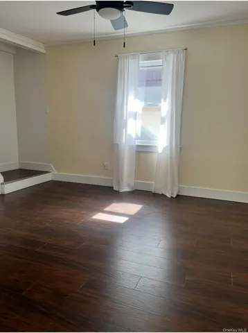 an empty room with wooden floor cabinet and windows