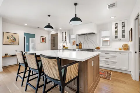 a kitchen with granite countertop white cabinets and chairs