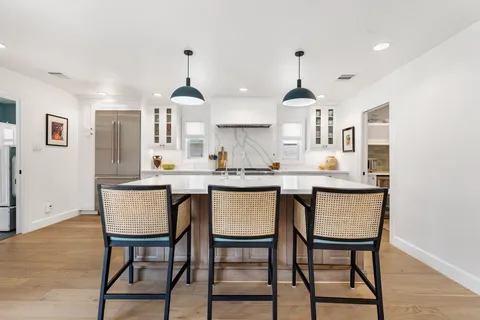 a kitchen with a sink stainless steel appliances a dining table and chairs