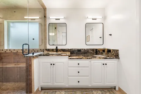 a bathroom with a granite countertop tub sink and mirror