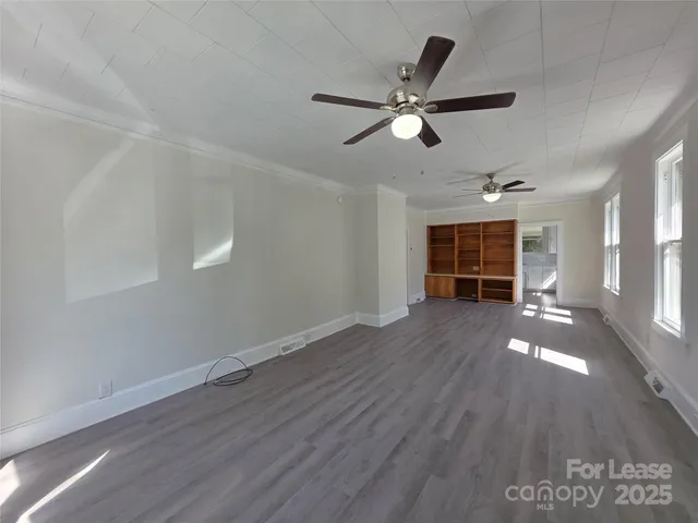 a view of empty room with wooden floor and window