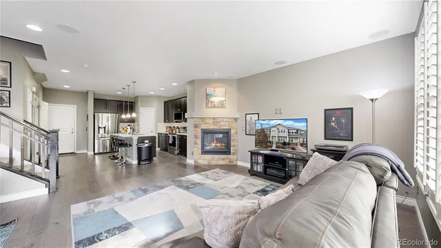 a living room with furniture a fireplace and a dining table with wooden floor