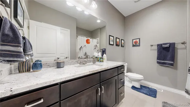 a bathroom with a granite countertop sink a toilet and a mirror