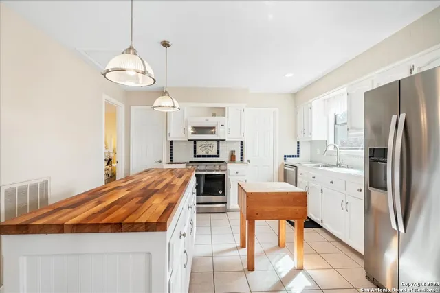 a kitchen with stainless steel appliances a stove a refrigerator and white cabinets