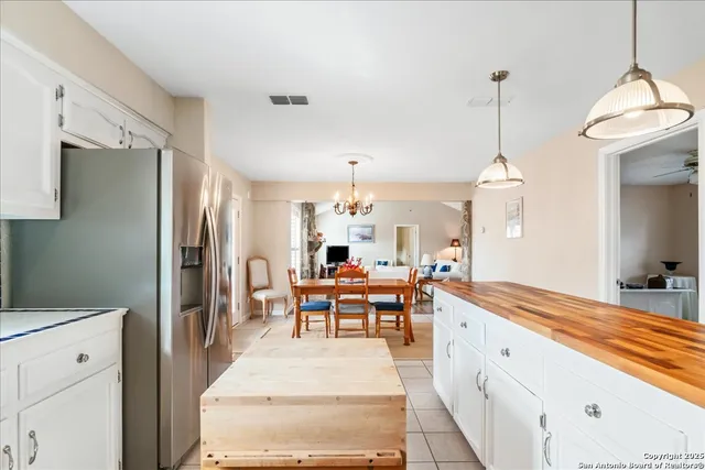 a living room with stainless steel appliances kitchen island granite countertop furniture and a chandelier