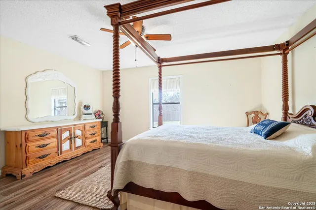 a bedroom with a bed a dresser with wooden floor