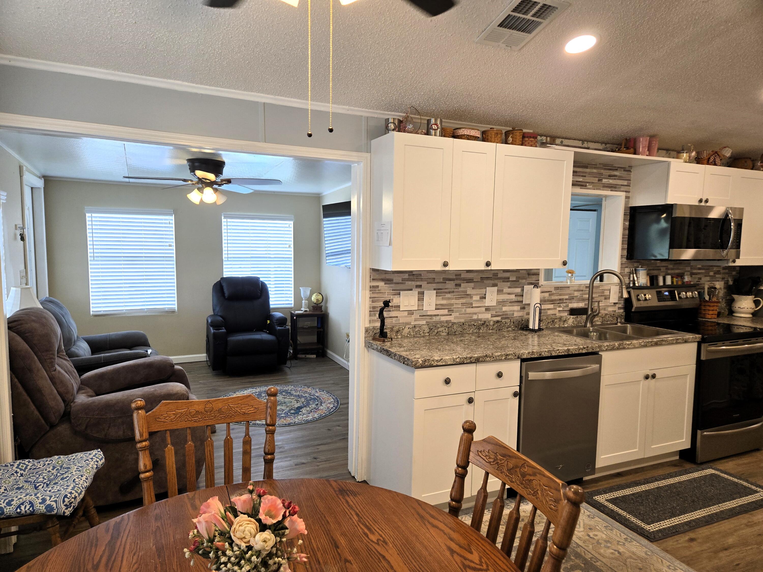 12240 Southeast 138th Avenue, Unit 225 Okeechobee, FL 34974 - Photo 12 of 50 a living room with furniture a flat screen tv and kitchen view