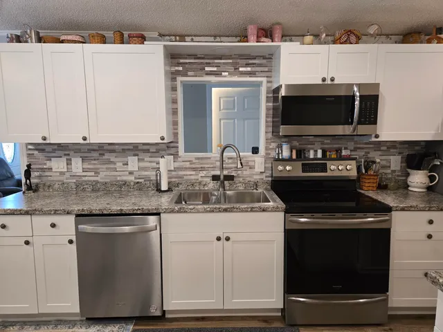 a kitchen with stainless steel appliances granite countertop a stove a sink and a microwave
