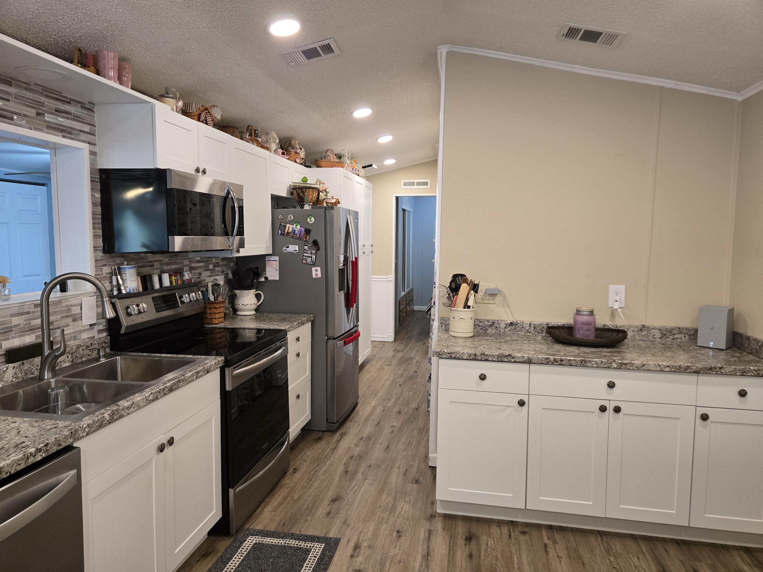 12240 Southeast 138th Avenue, Unit 225 Okeechobee, FL 34974 - Photo 16 of 50 a large kitchen with granite countertop a sink and a stove top oven with wooden floor