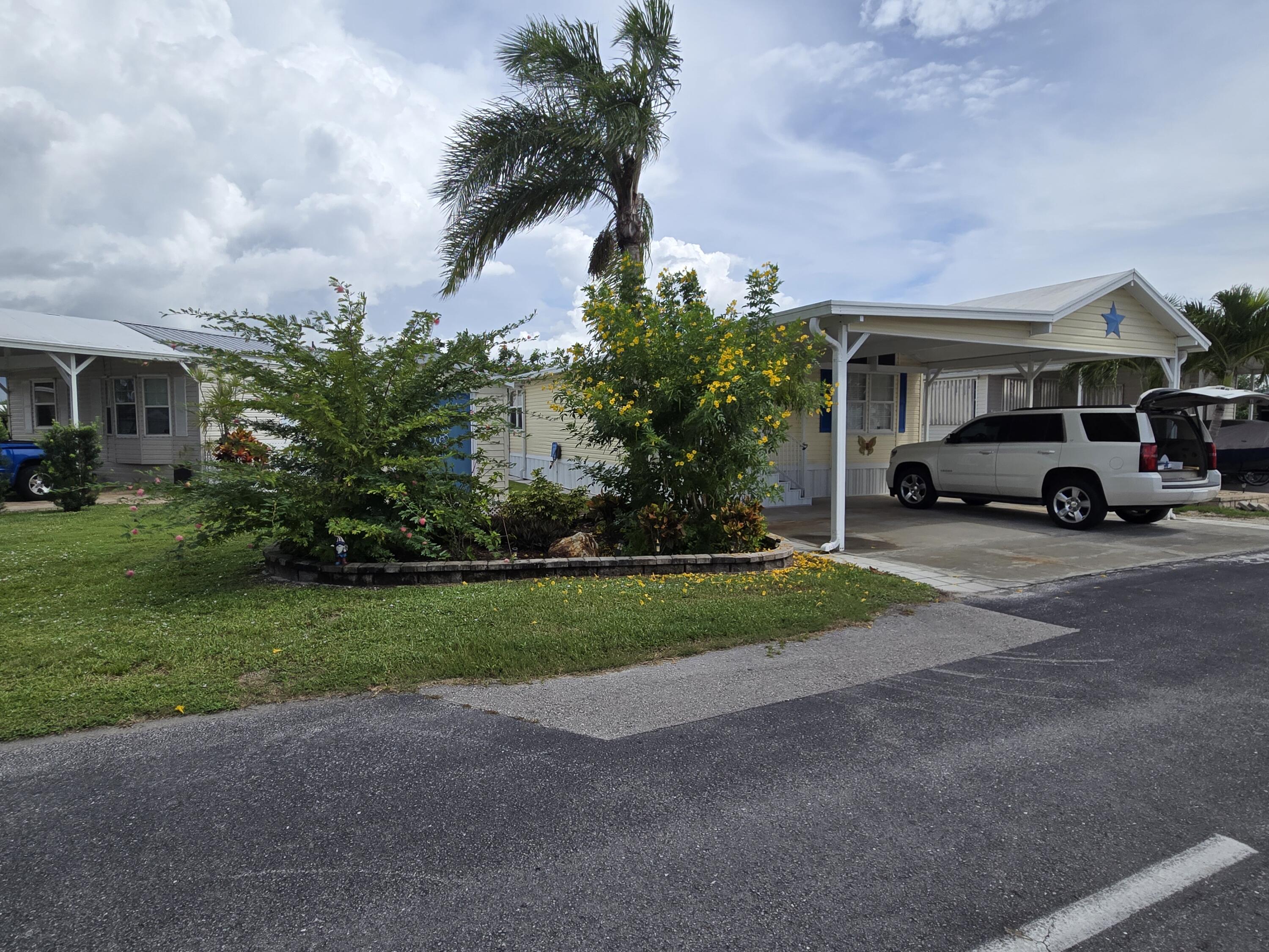 12240 Southeast 138th Avenue, Unit 225 Okeechobee, FL 34974 - Photo 38 of 50 a car parked in front of a house next to a yard