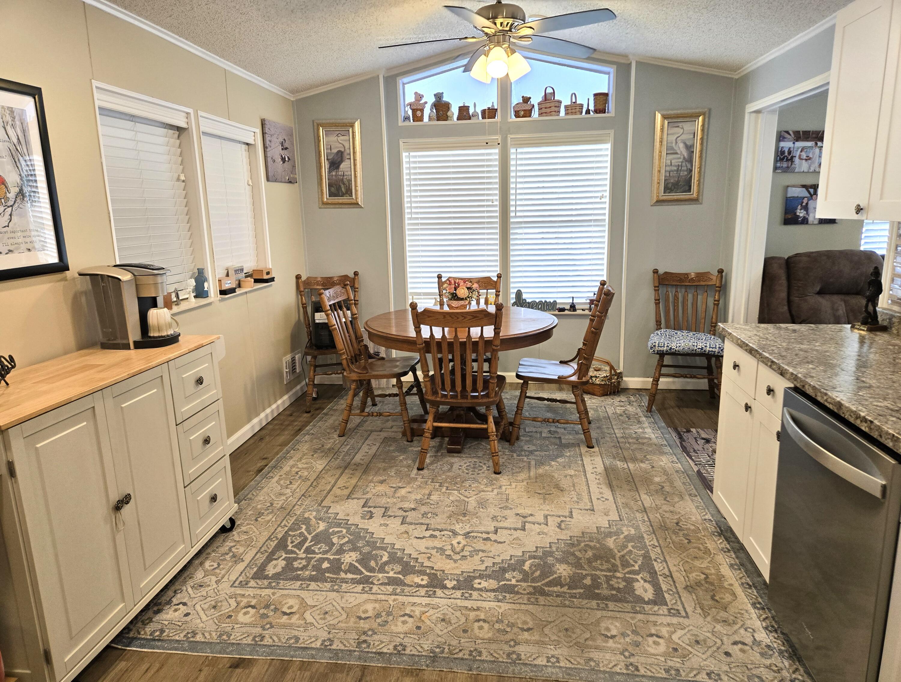 12240 Southeast 138th Avenue, Unit 225 Okeechobee, FL 34974 - Photo 9 of 50 a dining room with wooden floor a chandelier a wooden table and chairs