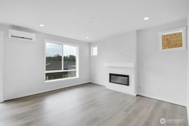 an empty room with wooden floor fireplace and windows