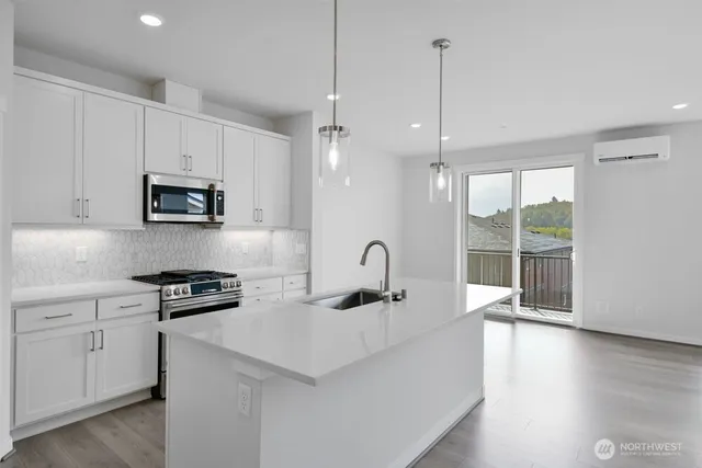 a kitchen with stainless steel appliances a sink a stove a microwave and wooden floor