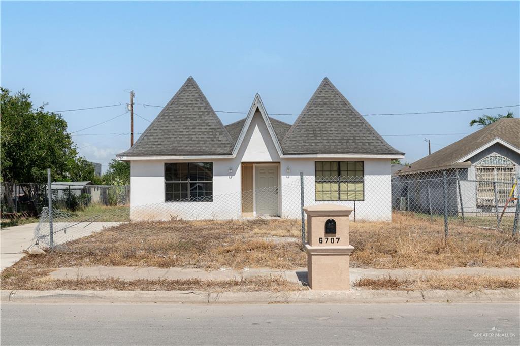 View of front of home with stucco siding and roof with shingles