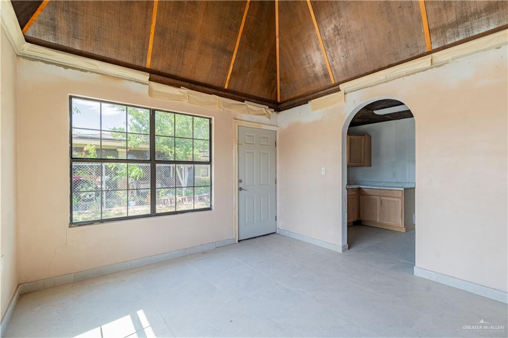 6707 South Rivera Street Pharr, TX 78577 - Photo 4 of 17 Empty room featuring arched walkways, light tile patterned floors, and a towering ceiling