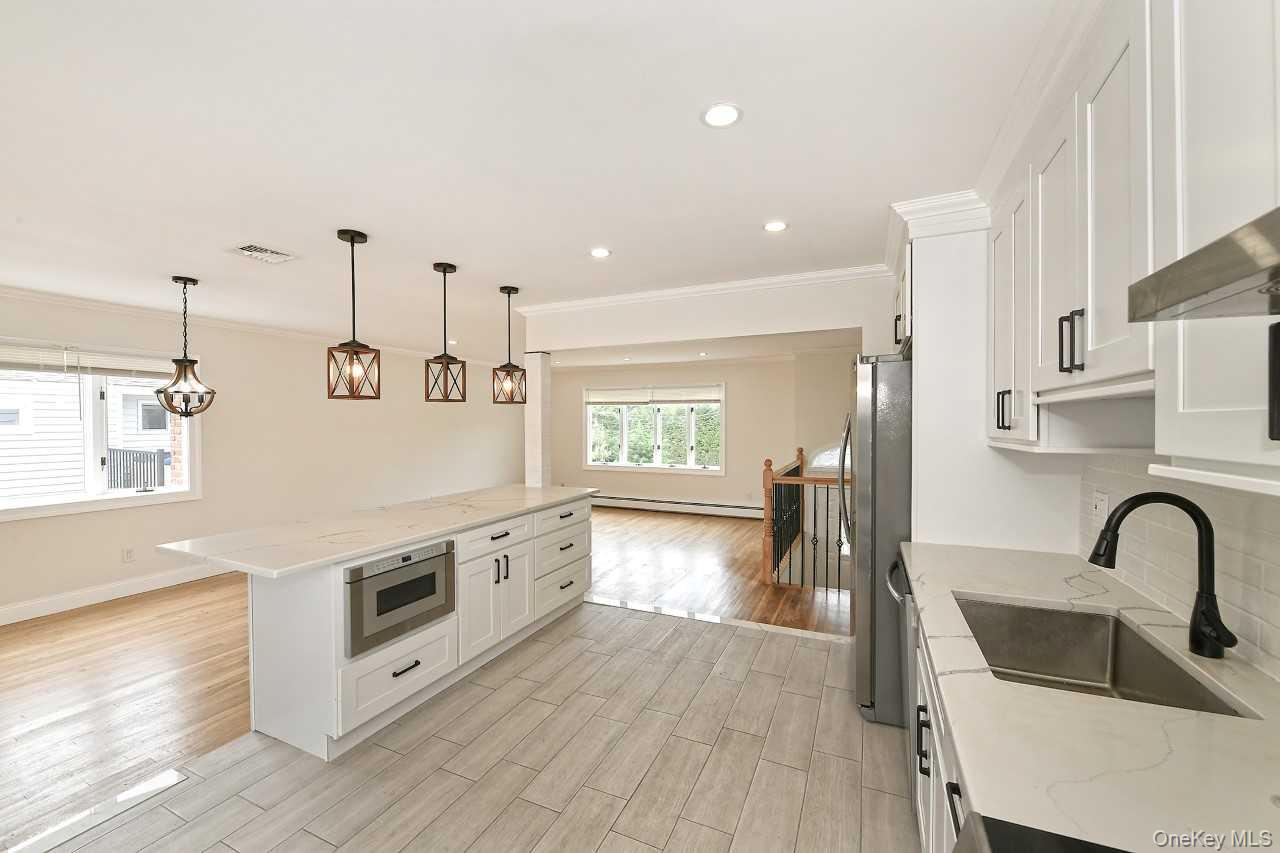 107 Beverly Road Massapequa, NY 11758 - Photo 12 of 41 a kitchen with stainless steel appliances granite countertop a sink a stove and a wooden floors