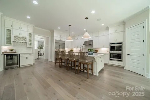 a kitchen with stainless steel appliances kitchen island granite countertop a table chairs sink and cabinets