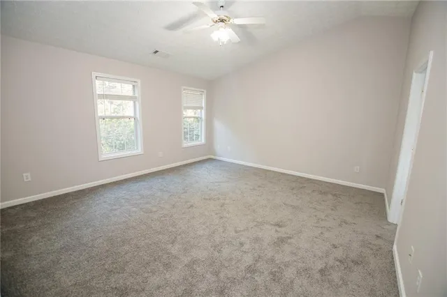 an empty room with windows and chandelier fan