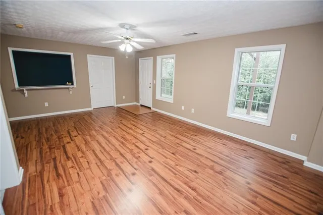 a view of an empty room with window and wooden floor