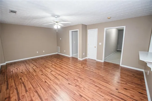 a view of a room with wooden floor and ceiling fan