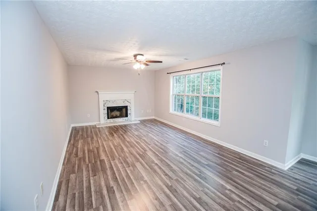 a view of an empty room with wooden floor fireplace and a window