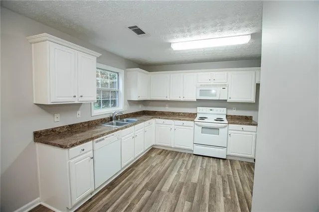 a kitchen with granite countertop white cabinets and white appliances