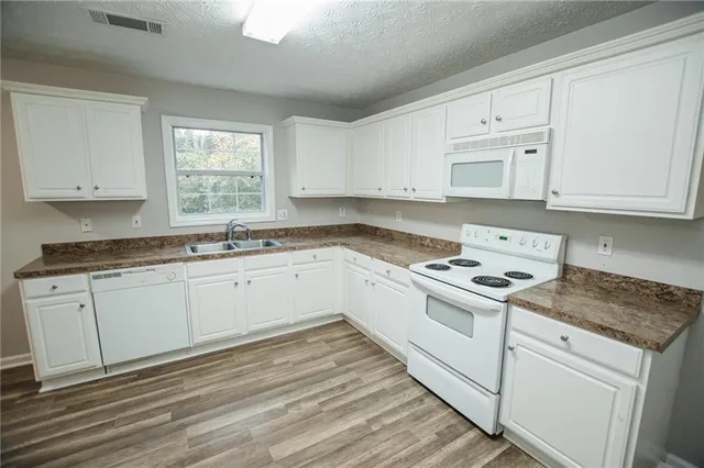 a kitchen with granite countertop white cabinets and white appliances