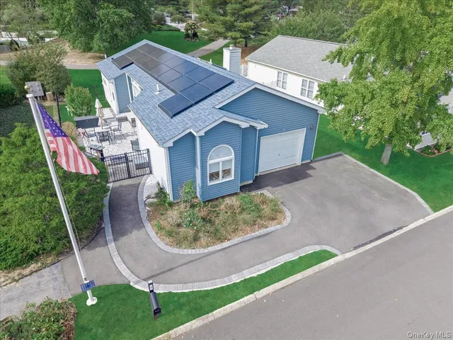 an aerial view of a house with a yard and large tree