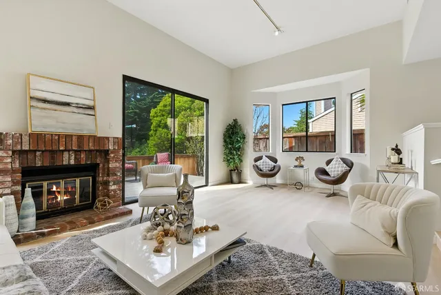 a living room with furniture a fireplace a large window and a flat screen tv