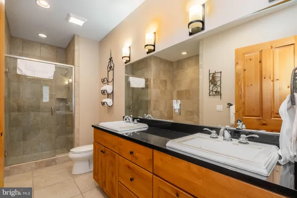 a bathroom with a double vanity sink toilet mirror and shower