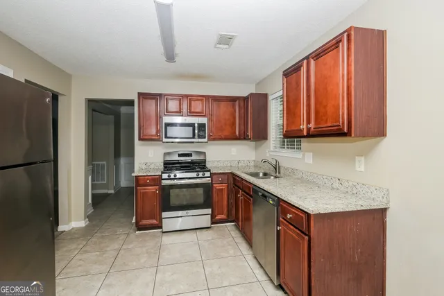 a kitchen with stainless steel appliances granite countertop a stove top oven a refrigerator and a sink