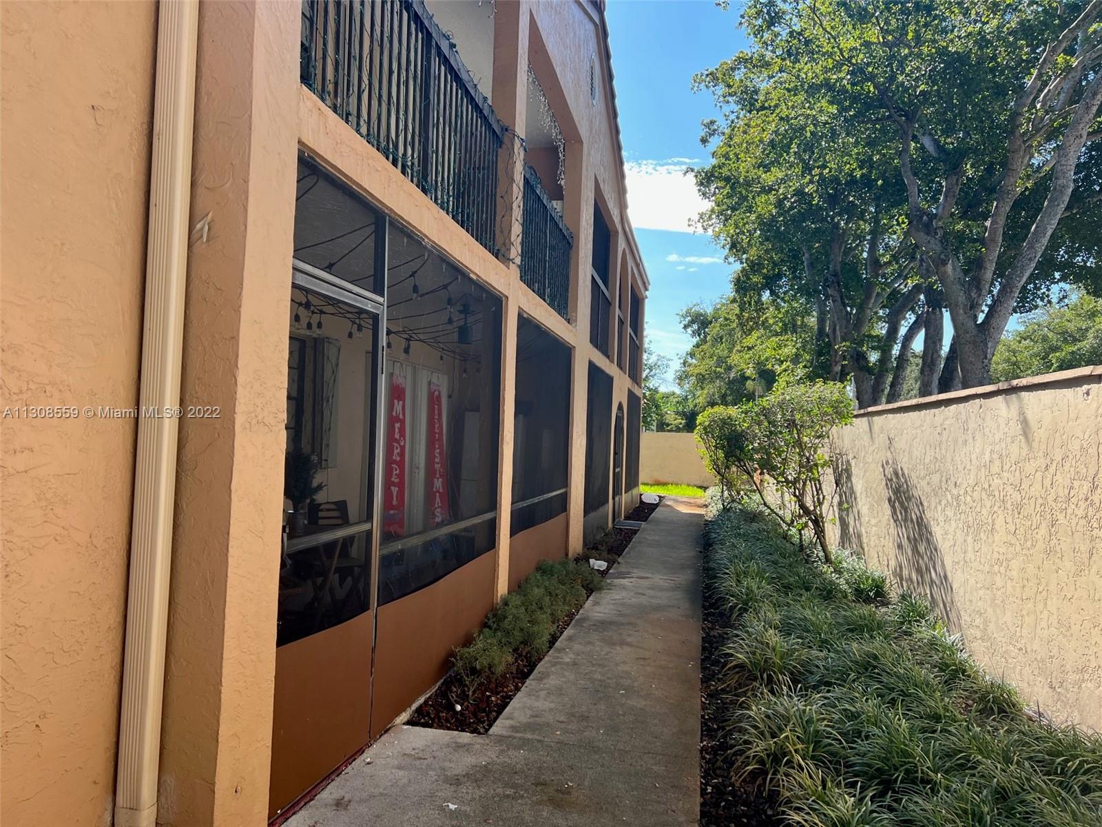 18230 Mediterranean Boulevard, Unit 113 Hialeah, FL 33015 - Photo 2 of 18 a view of a pathway of a house with wooden fence