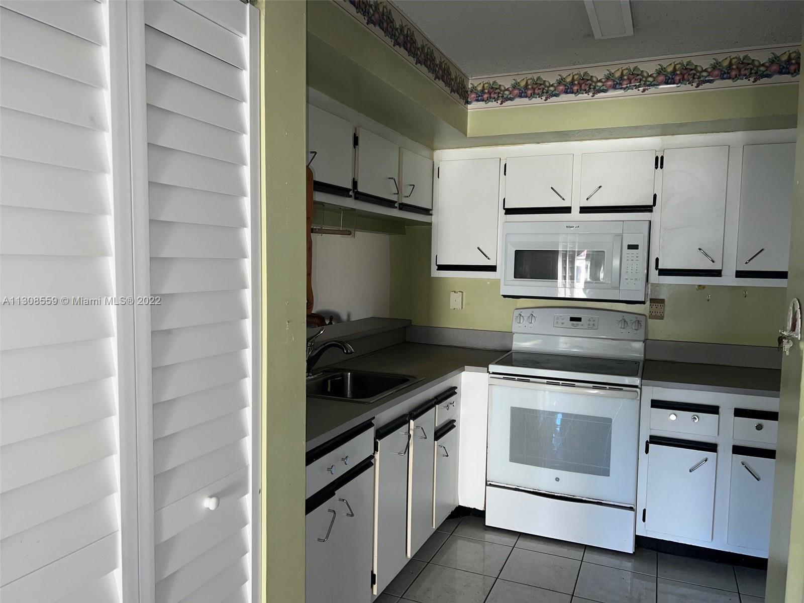 18230 Mediterranean Boulevard, Unit 113 Hialeah, FL 33015 - Photo 6 of 18 a kitchen with white cabinets and appliances